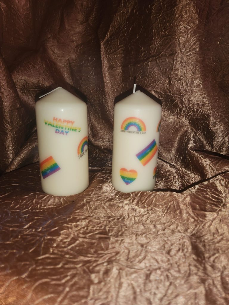 Our LGBTQ+ candles are covered in rainbows and rainbow flags with the message happy valentine’s day and love is love.